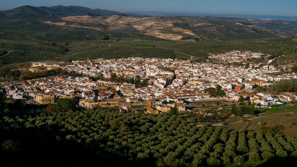 Dona Mencia town surrounded by olive trees landscape at sunrise, Sierra Subbetica, Cordoba, Andalusia, Spain. View from peak Oreja de la Mula, hiking destination. High quality photo