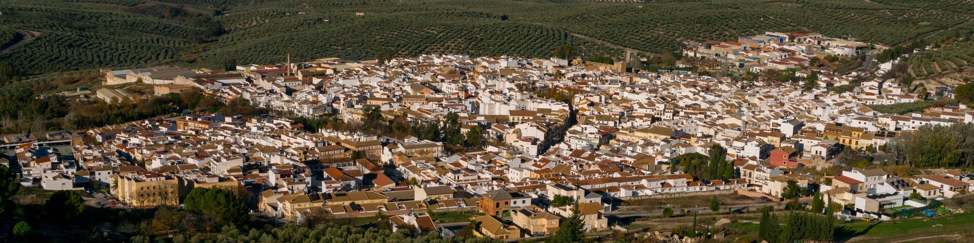 Dona Mencia town surrounded by olive trees landscape at sunrise, Sierra Subbetica, Cordoba, Andalusia, Spain. View from peak Oreja de la Mula, hiking destination. High quality photo