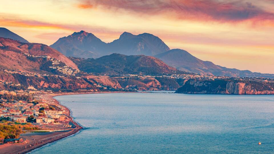 A coastal town with mountains in the background and a clear sky.