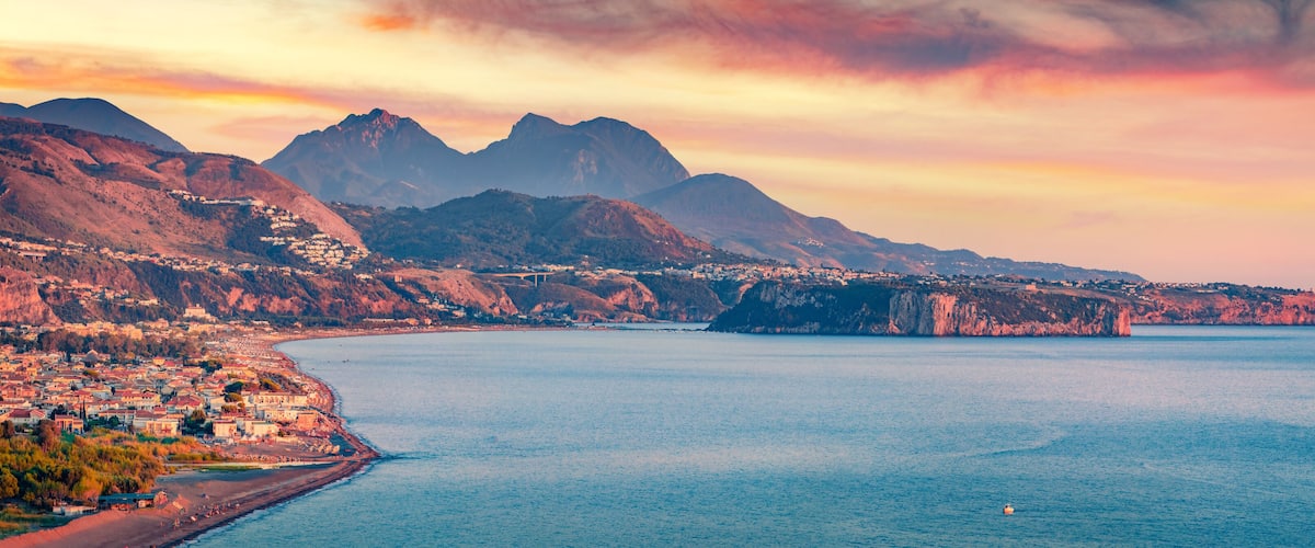 A coastal town with mountains in the background and a clear sky.