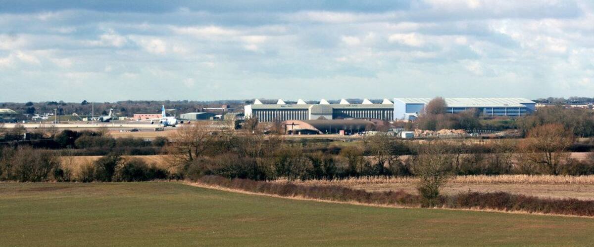 A grassy field with a large industrial building in the background.
