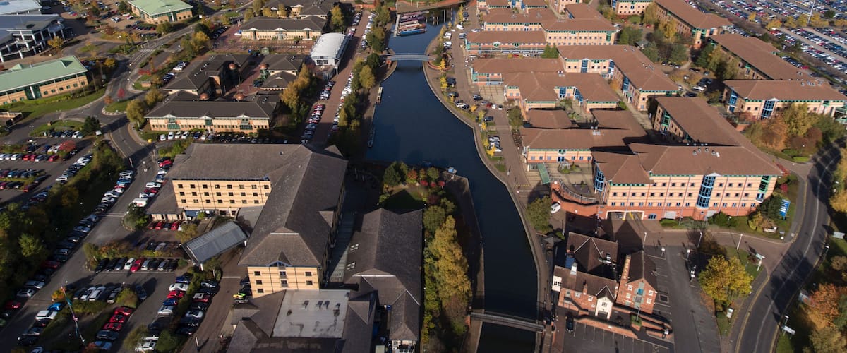 An aerial view of a city with a river, buildings, and a parking lot.