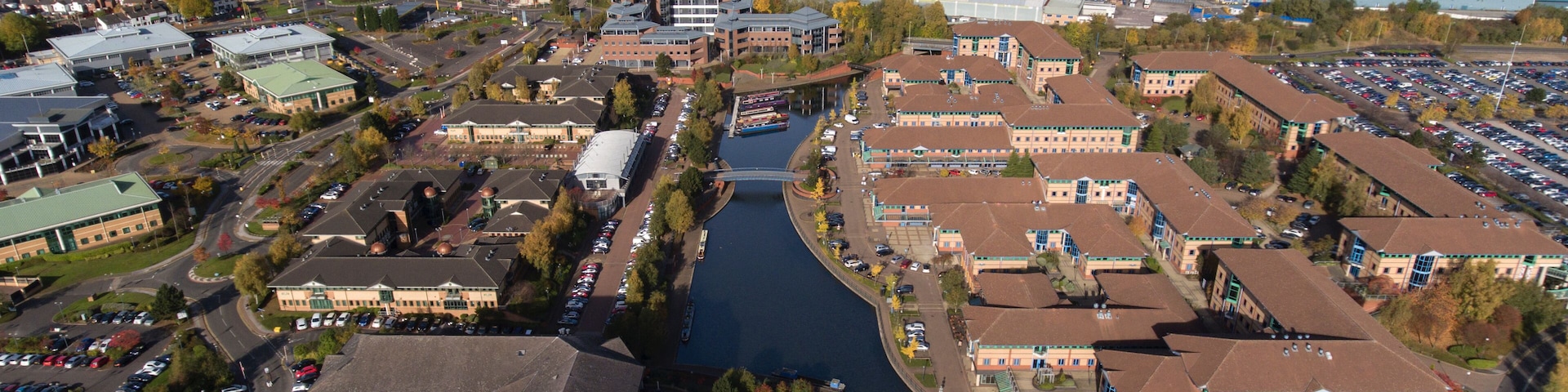 An aerial view of a city with a river, buildings, and a parking lot.