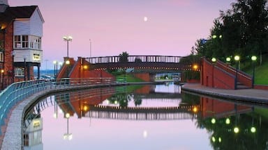 Um rio calmo com uma ponte, um edifício com varanda e o reflexo do céu.