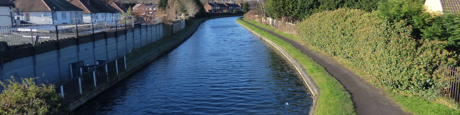 A narrow canal flanked by houses and greenery.