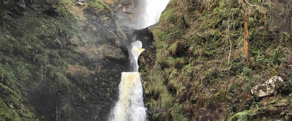 A waterfall cascading down a rocky cliff into a river.
