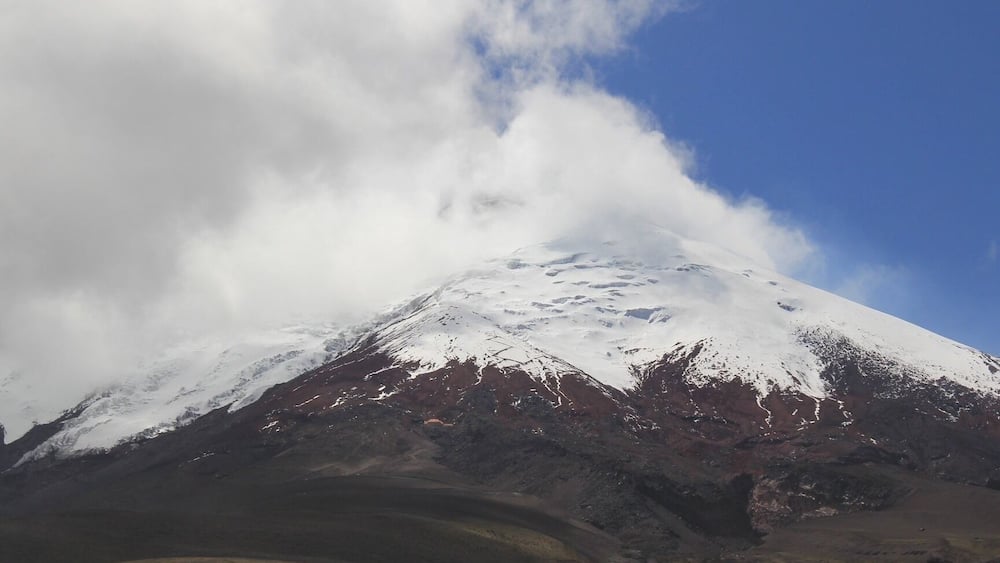 A snow-capped mountain with a clear sky and clouds.