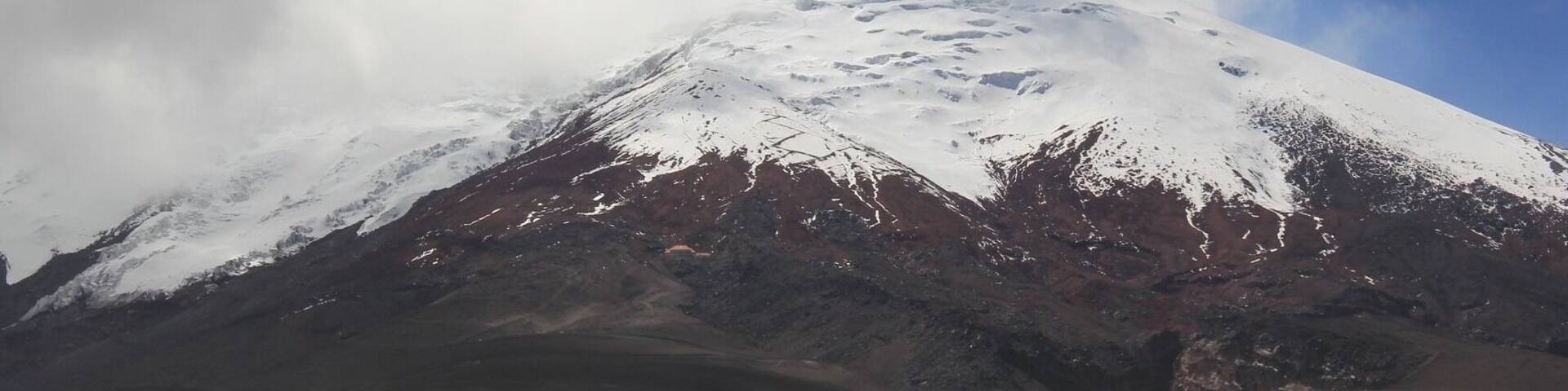 A snow-capped mountain with a clear sky and clouds.