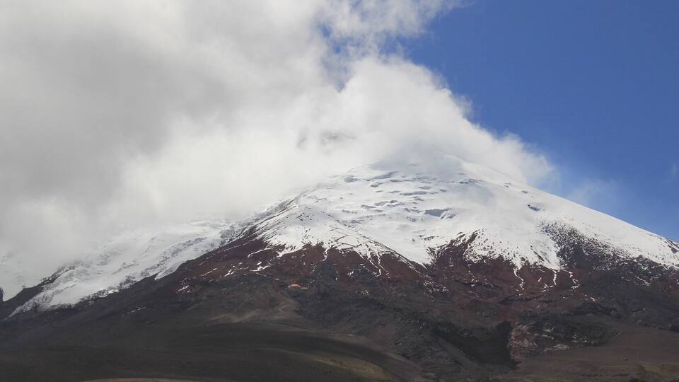 A snow-capped mountain with a clear sky and clouds.