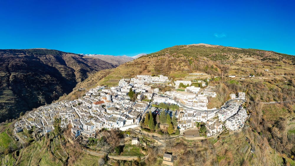 Un village de montagne aux maisons blanches, niché dans une vallée.