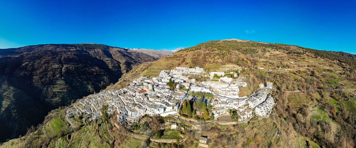 A mountainous village with white buildings nestled in a valley.