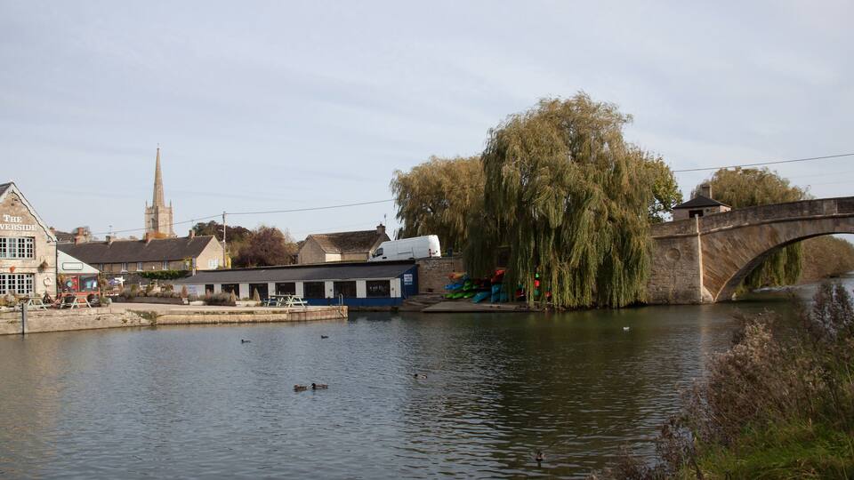 A riverside view with a bridge, a church spire, and a pub named 'The Riverside'.