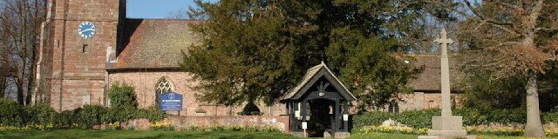 A church with a clock tower, a cross monument, and a small chapel.