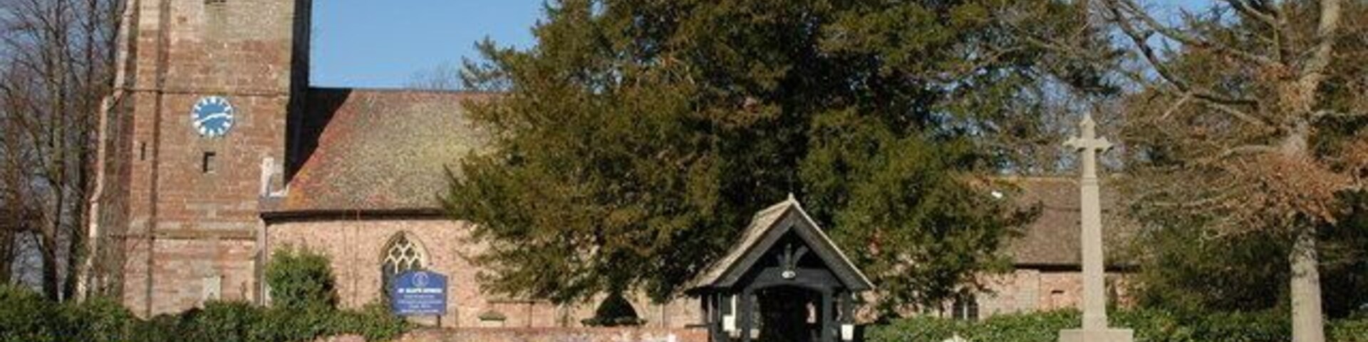 Una iglesia con una torre de reloj, un monumento con una cruz y una pequeña capilla.
