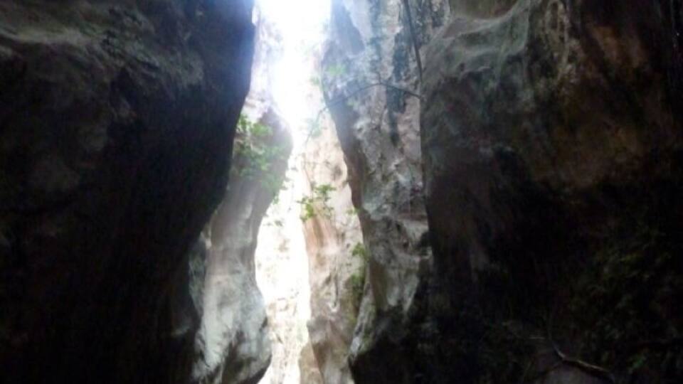 A narrow canyon with rocky walls and sunlight filtering through.