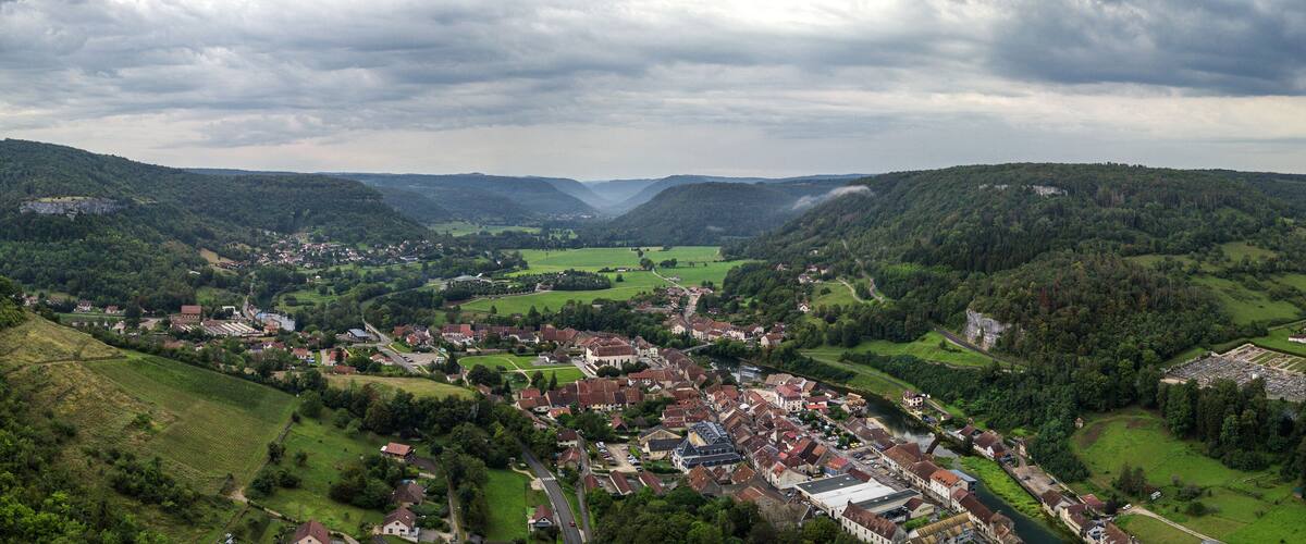 A valley town surrounded by hills and mountains, with a river running through the center.