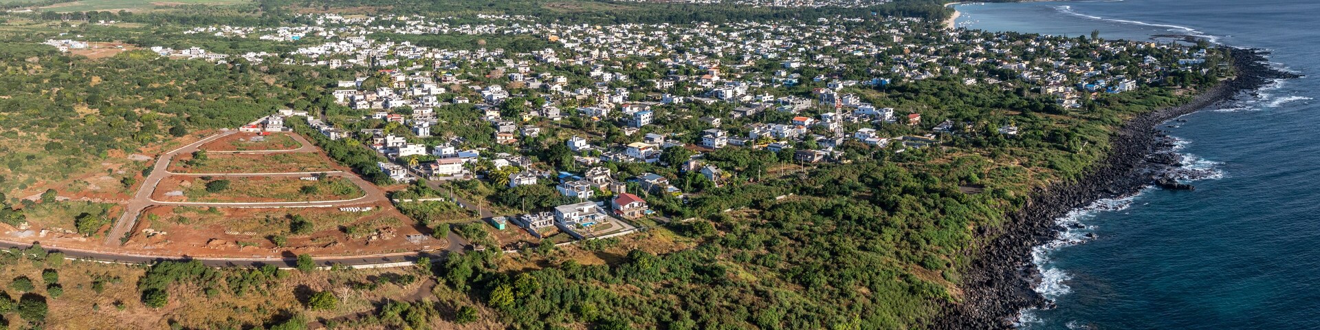 panoramic aerial landscape view of Mauritius west coast with steep cliffs, the city of Albion in front and Mauritius mountain landscape in background