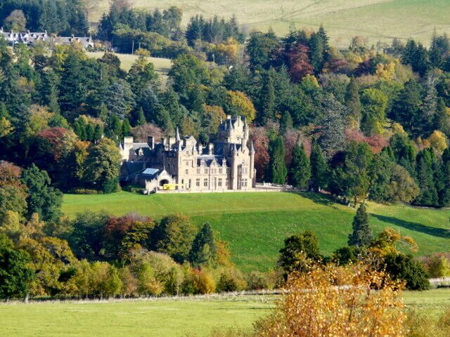 A castle surrounded by a lush green landscape with trees and rolling hills.