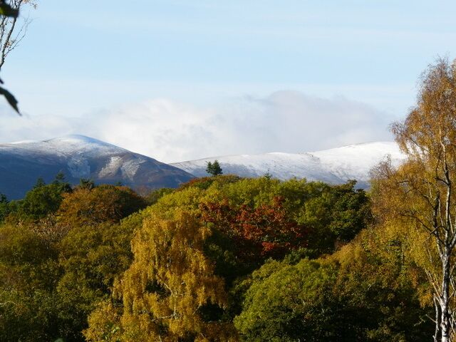 A mountainous landscape with autumn foliage and snow-capped peaks.