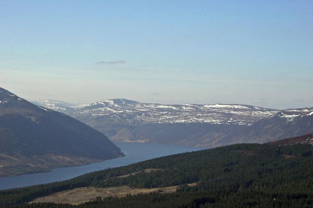 A mountainous landscape with a lake and snow-capped peaks.