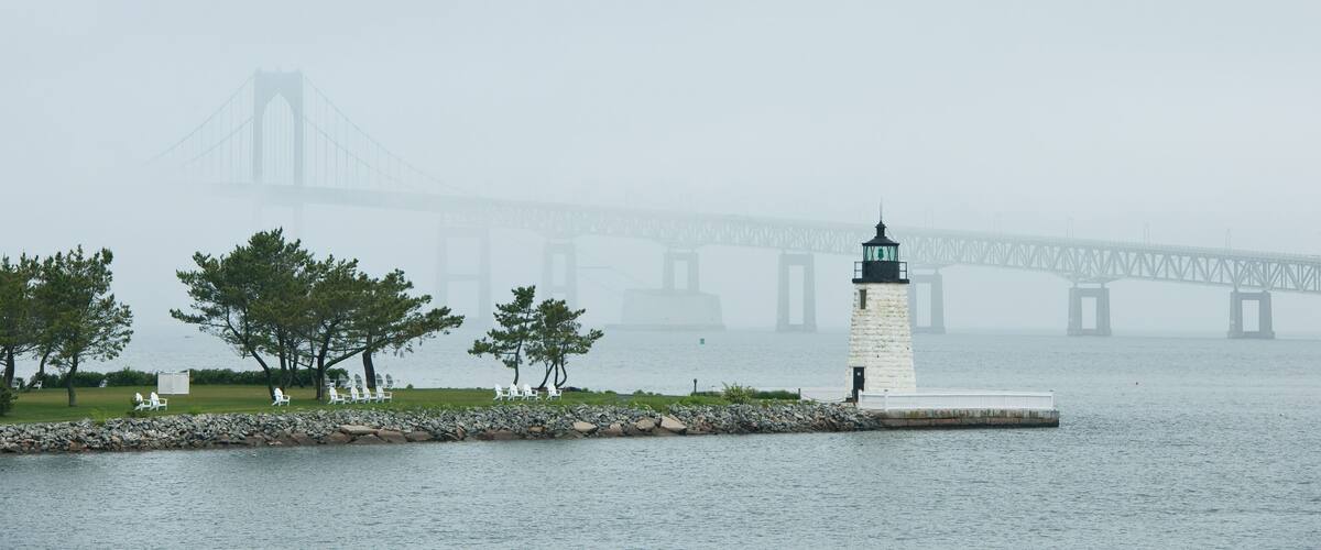 A lighthouse and a bridge in the fog.