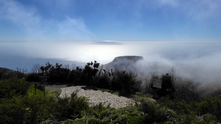 A rocky landscape with a cliff overlooking a misty coastline.