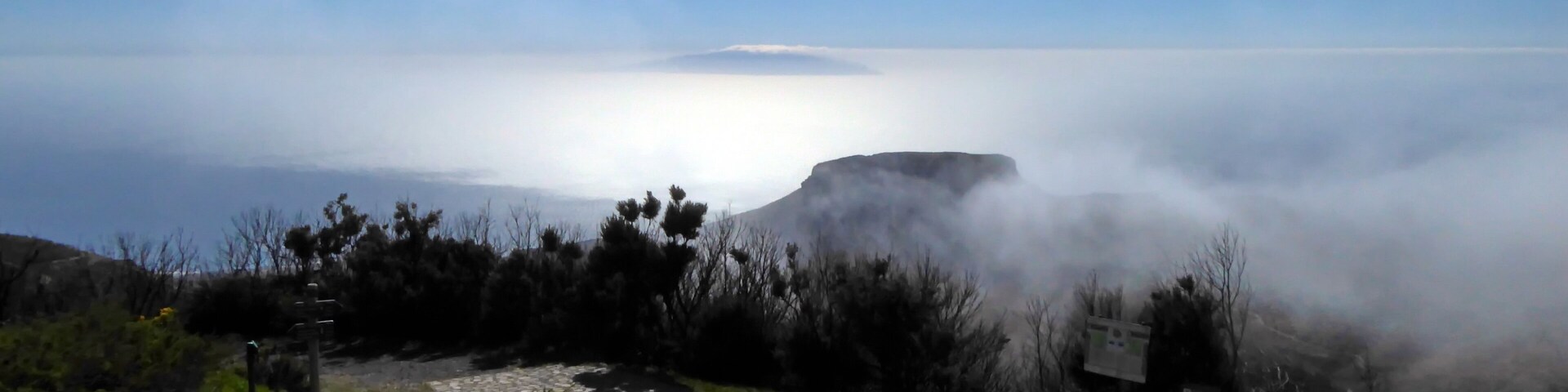 A rocky landscape with a cliff overlooking a misty coastline.