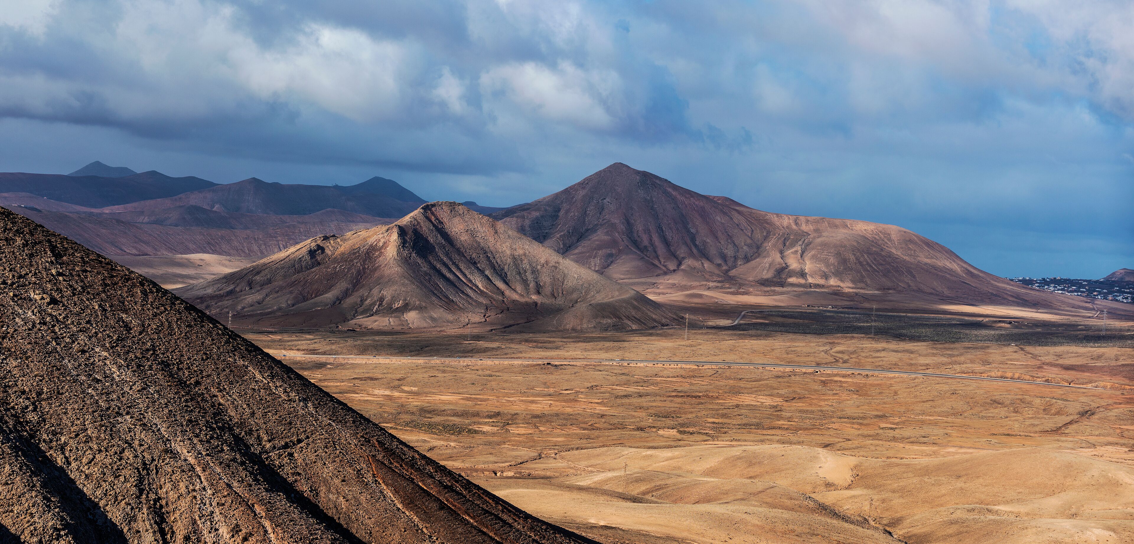 Paisaje desértico con montañas imponentes y un camino sinuoso.