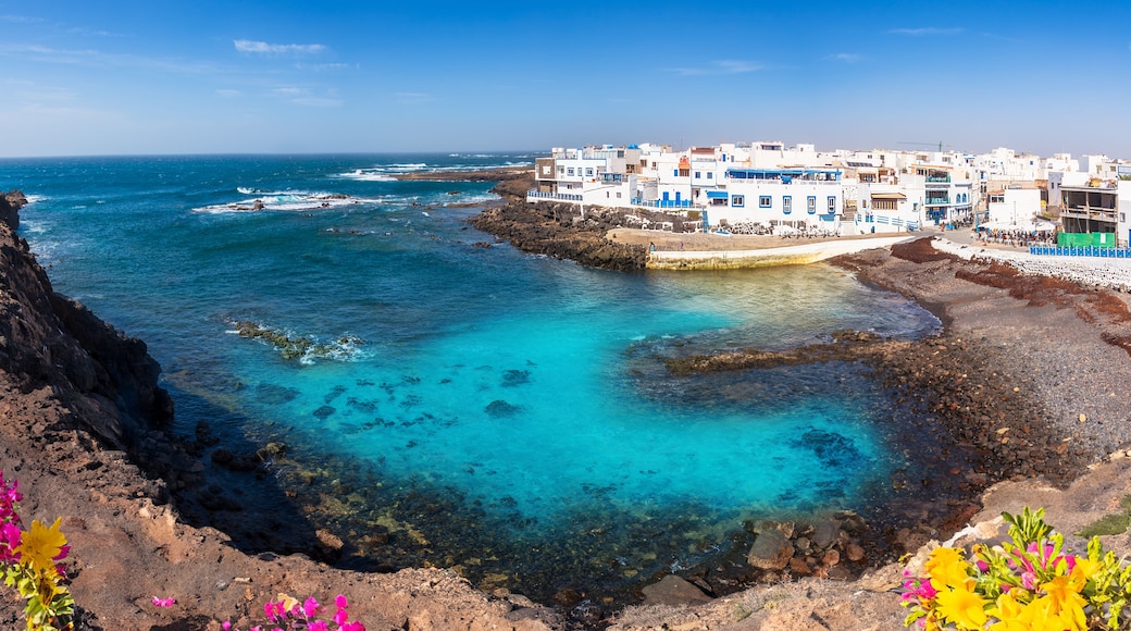A coastal town with white buildings, clear turquoise waters, and rocky shores.