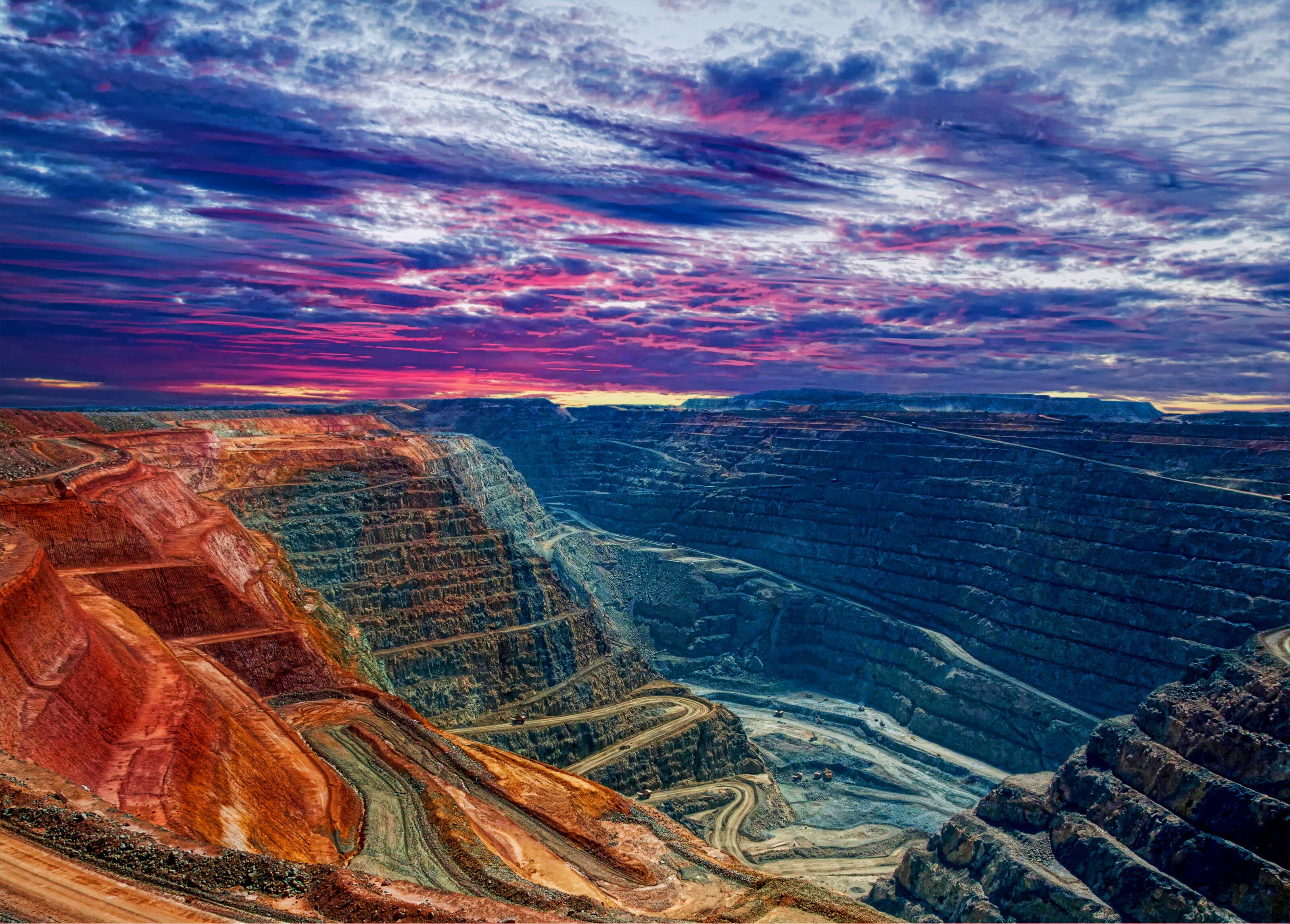 A vast canyon with layered rock formations and winding roads.