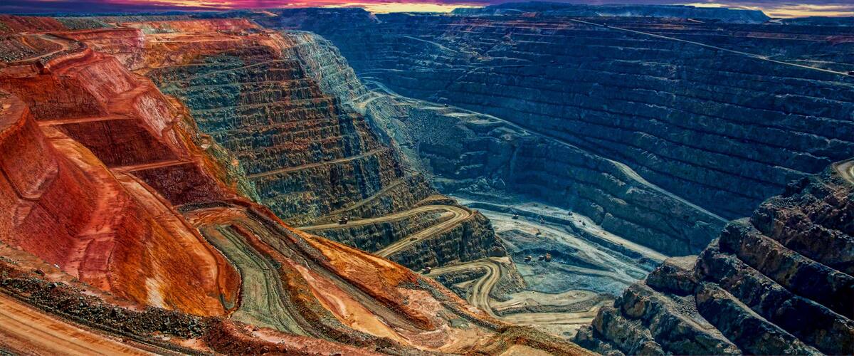 A vast canyon with layered rock formations and winding roads.