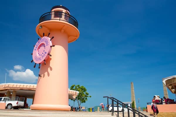 Un phare rose avec un panneau circulaire, un camion blanc et des personnes à l’arrière-plan.