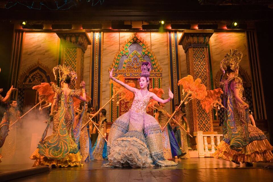 A stage with performers in elaborate costumes and a traditional architectural backdrop.