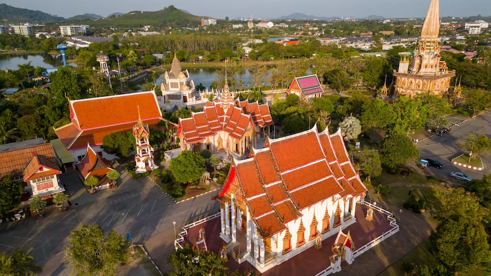 A temple complex with multiple structures, a large body of water, and surrounding greenery.
