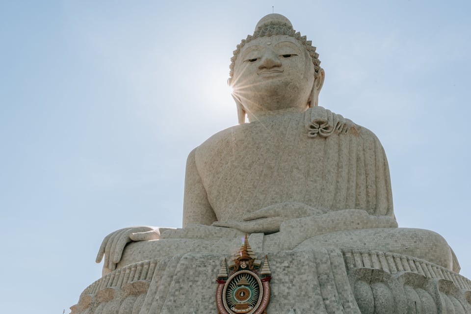 A large stone Buddha statue with intricate carvings and a golden emblem at its base.
