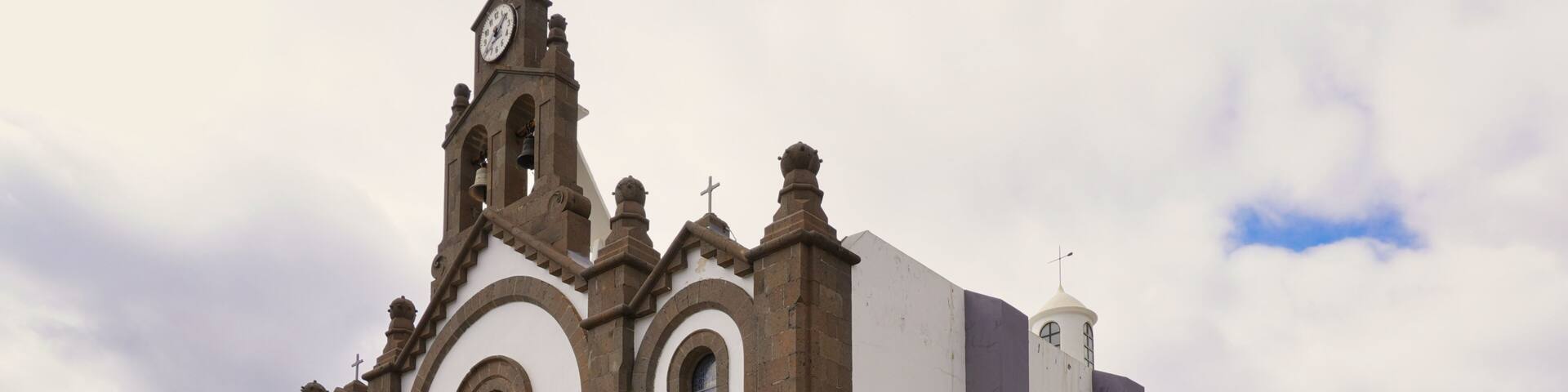 A historic church with a clock tower, arched windows, and a prominent bell.