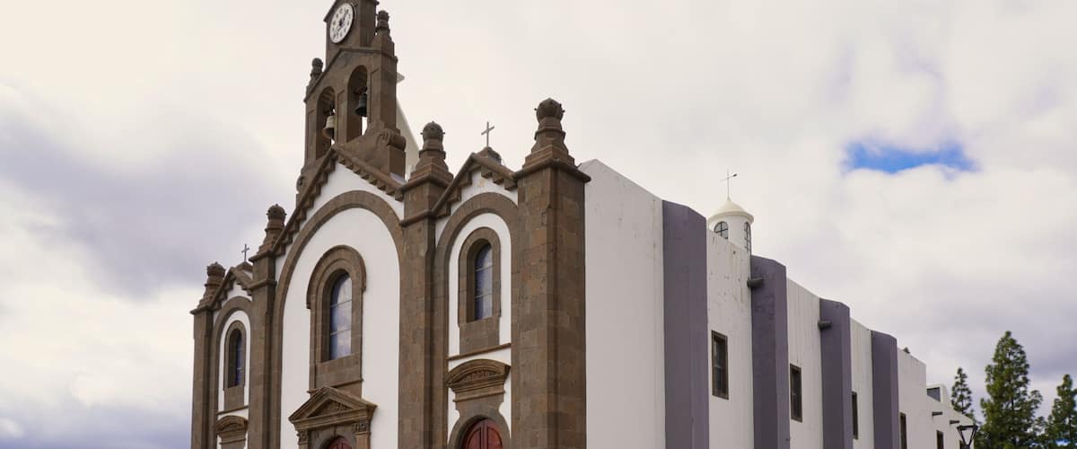 A historic church with a clock tower, arched windows, and a prominent bell.