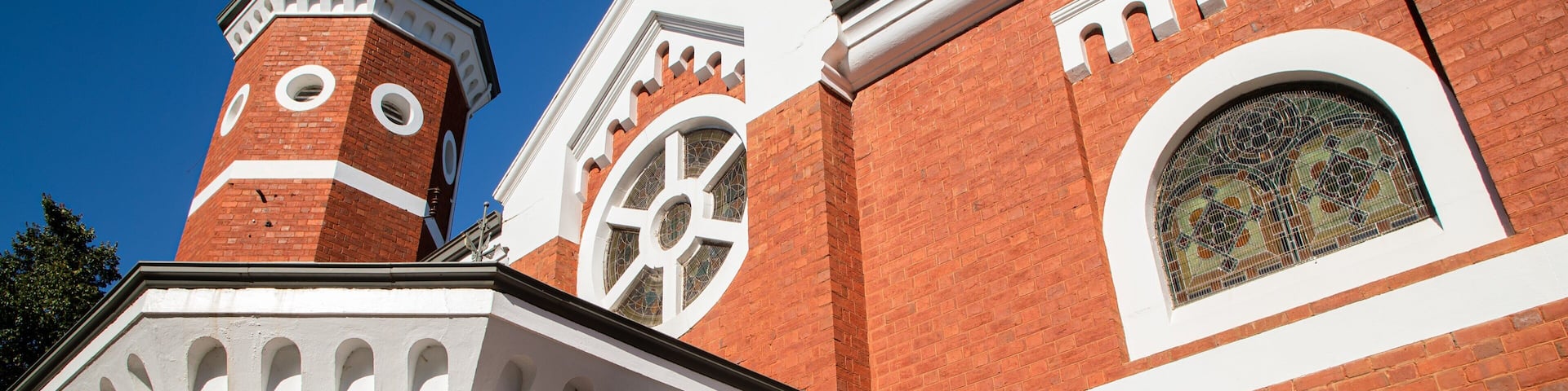 A red brick church with a white steeple and a large circular window.