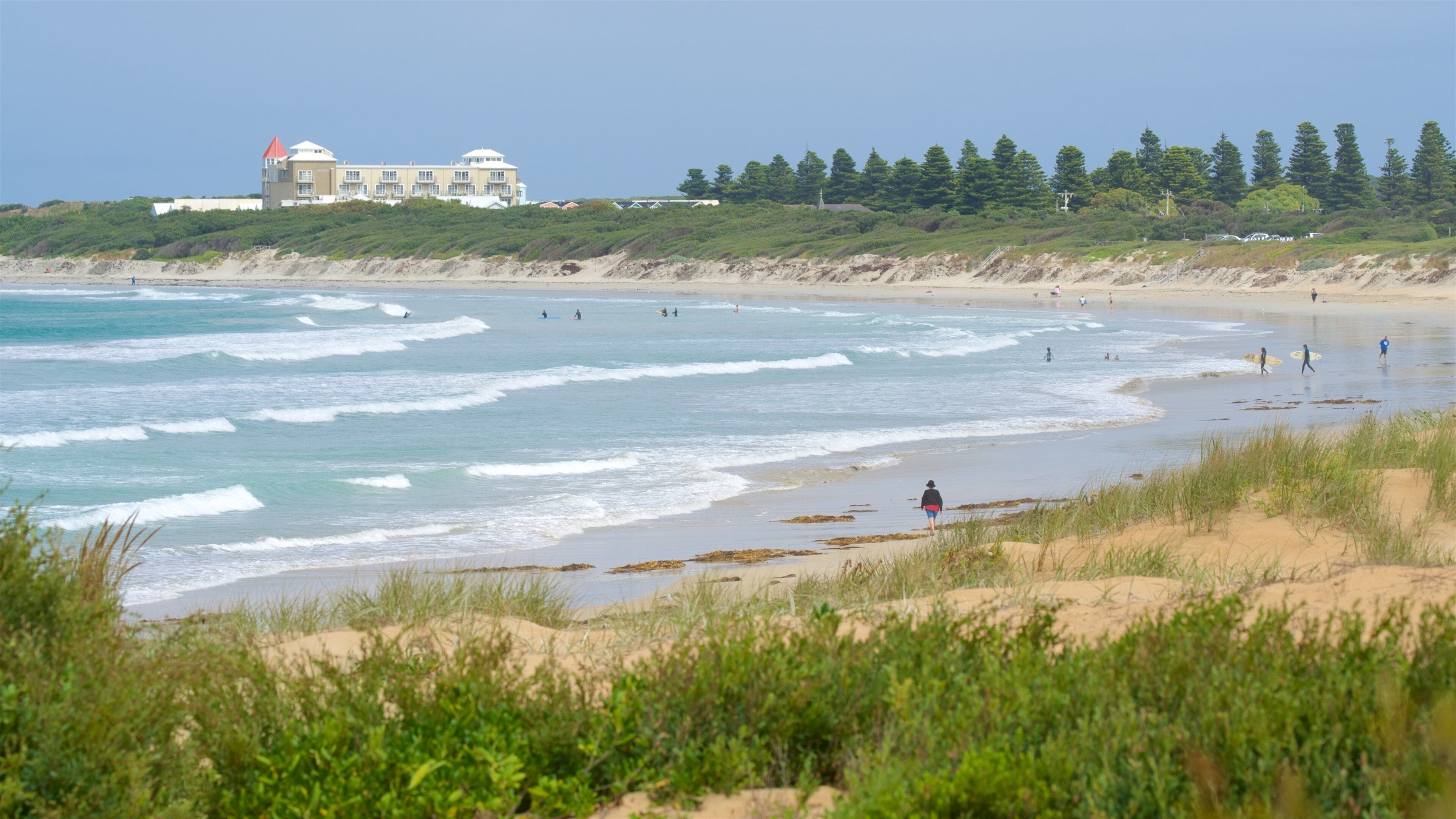 Una playa con olas, un edificio y árboles.