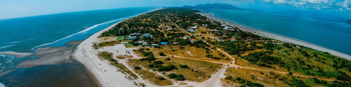A coastal landscape with a beach, a small settlement, and a clear blue sky.