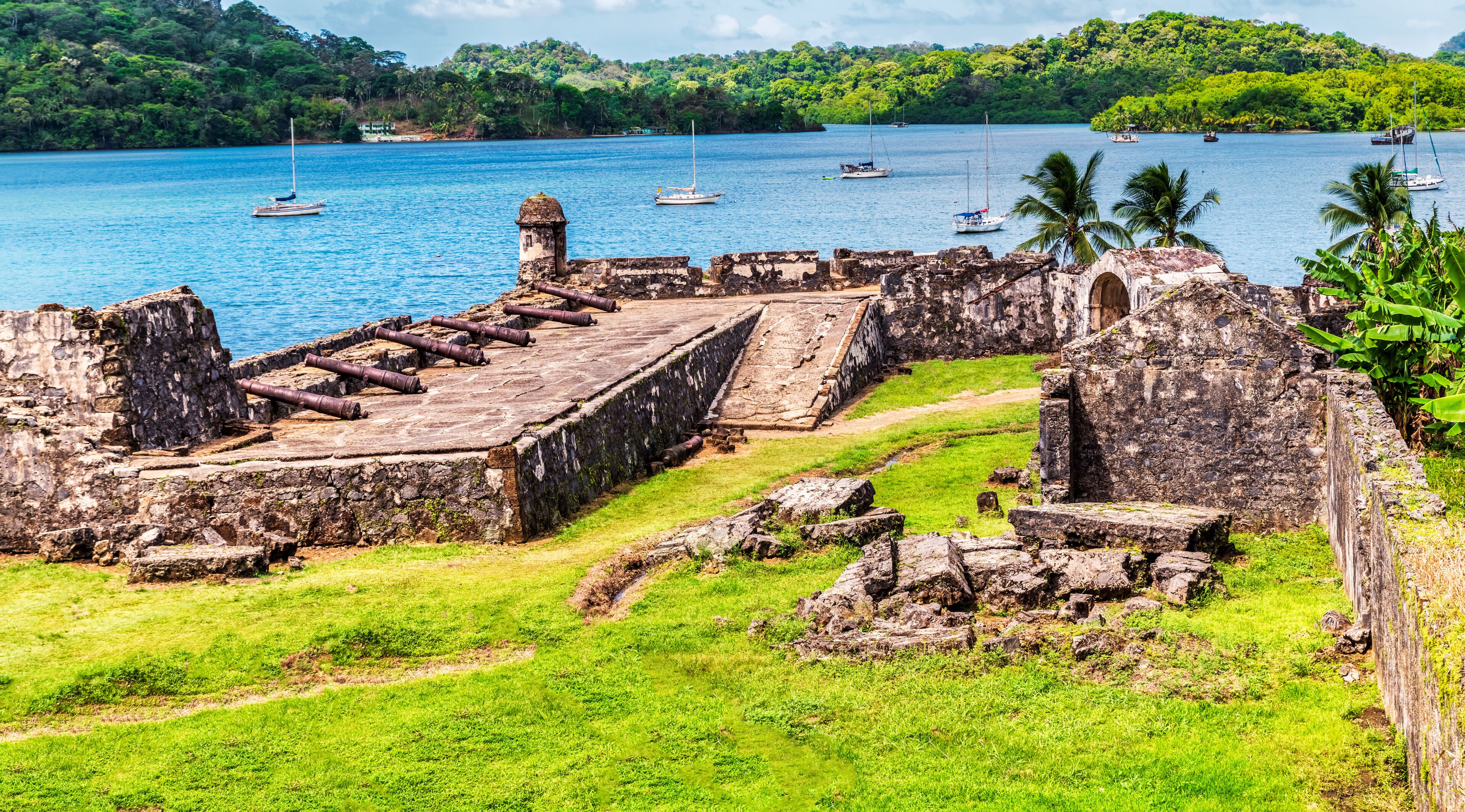 A coastal archaeological site with ruins and a clear blue sea.