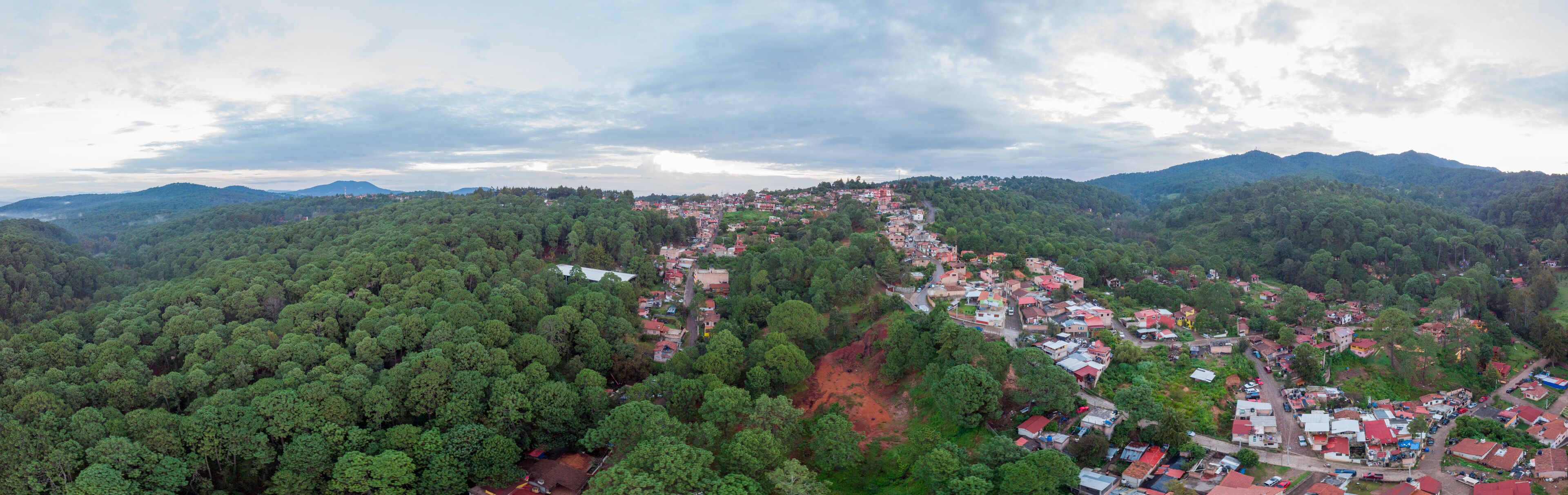Aerial shot of the sunrise of the magical town Mazamitla surrounded by a beautiful green valley with surrounding mountains. Mazamitla, Jalisco, Mexico