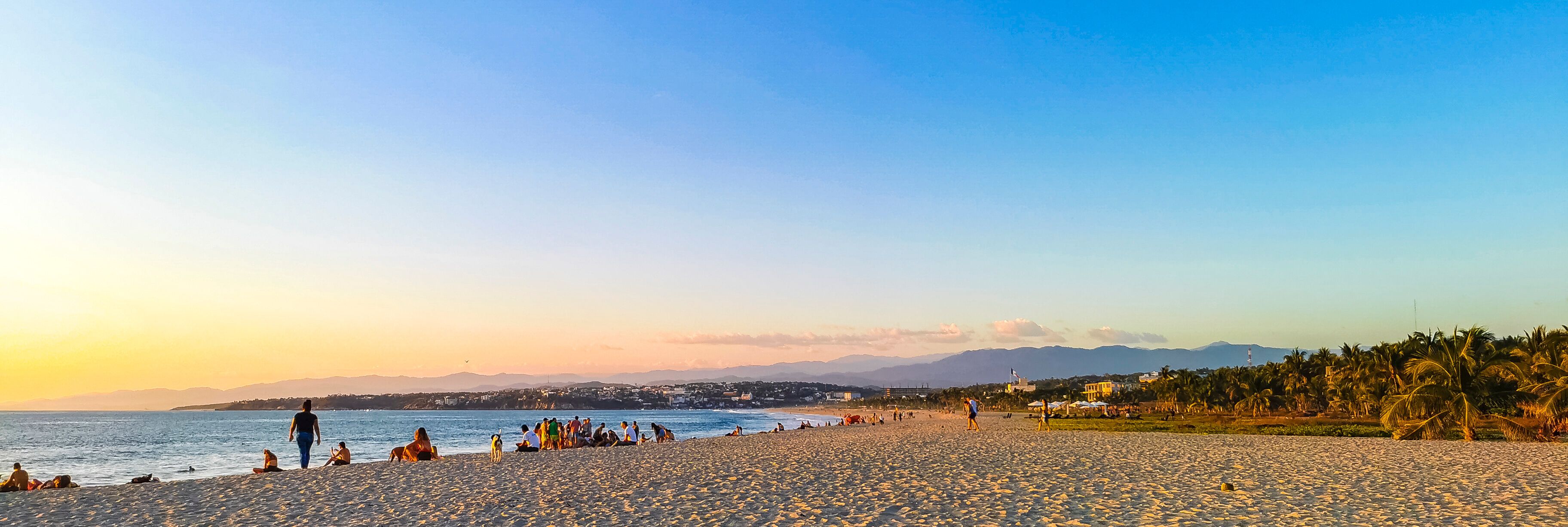 Colorful golden sunset people wave and beach Puerto Escondido Mexico.