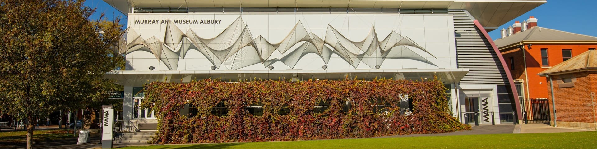 The Murray Art Museum Albury with a modern architectural design, featuring a white facade and a green lawn in front.