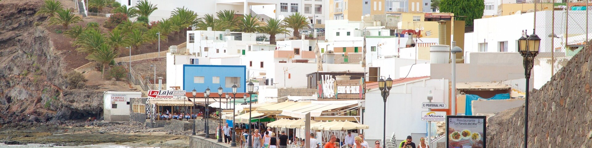 A coastal town with white buildings, a beach, and a rocky cliff.