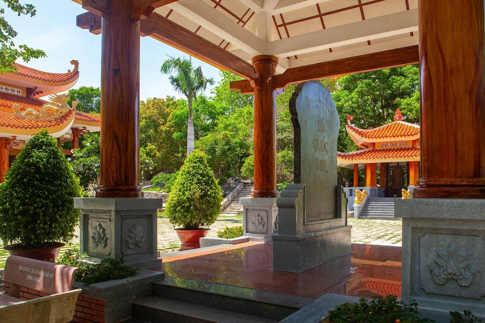 A traditional temple with wooden pillars, stone statues, and a tiled roof.