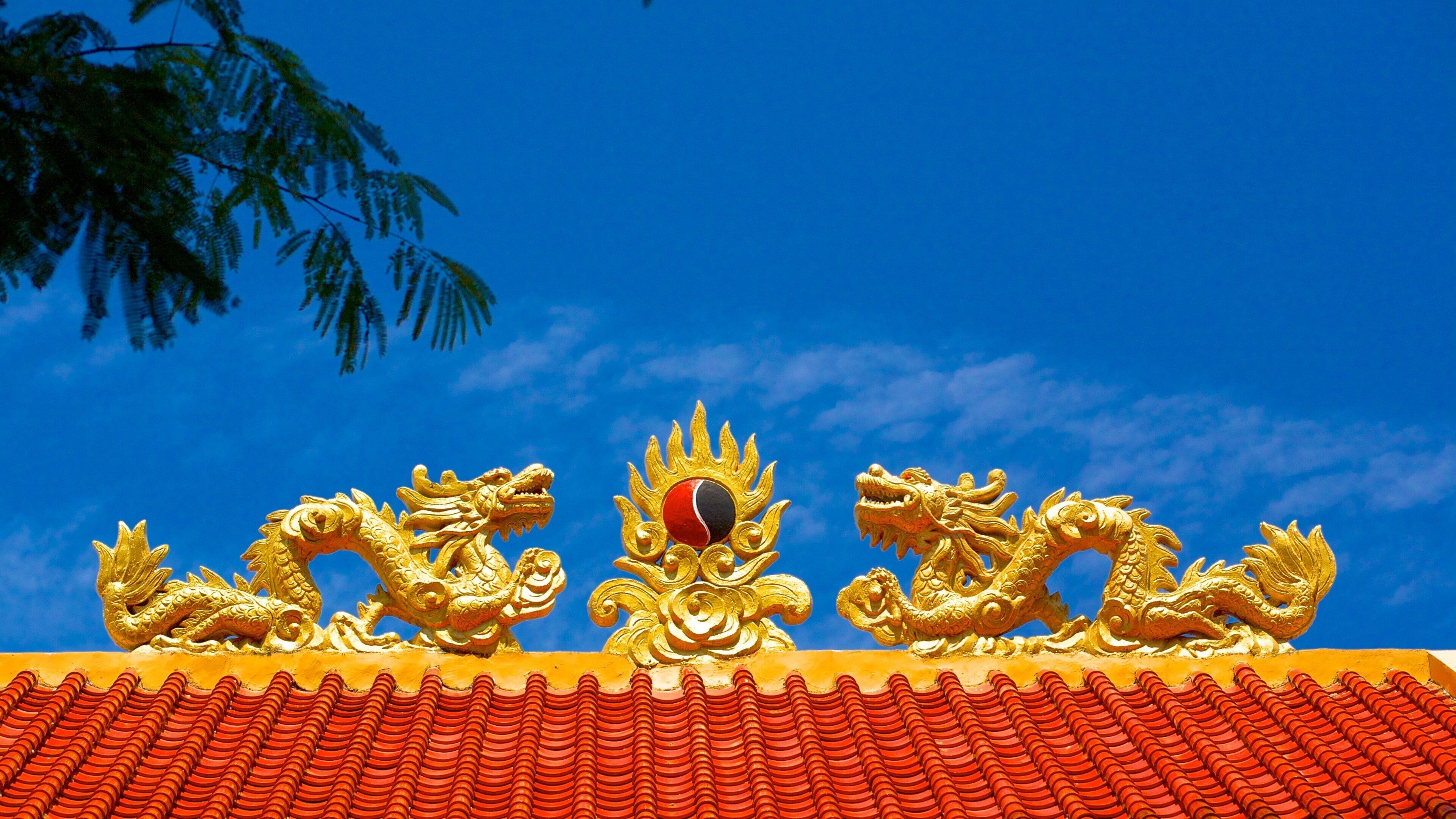 A traditional roof with golden dragon sculptures and a red and black emblem.