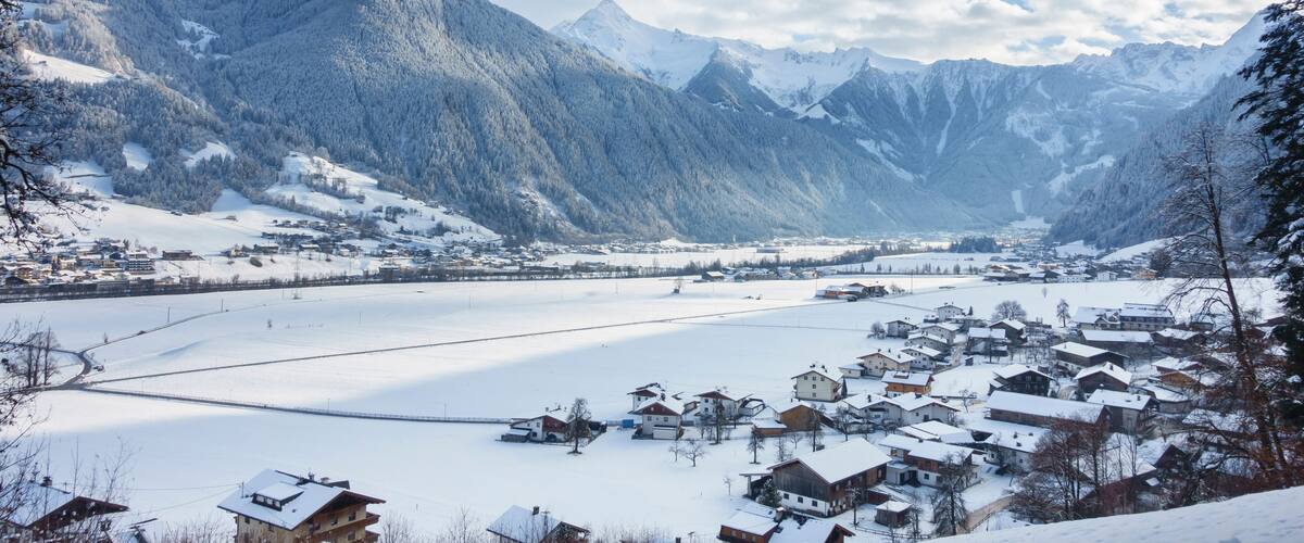 A snow-covered village nestled in a valley with mountains in the background.