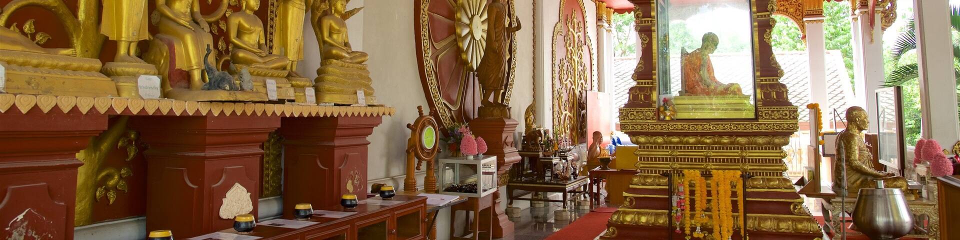 A temple interior with golden statues, a central altar, and intricate wall carvings.