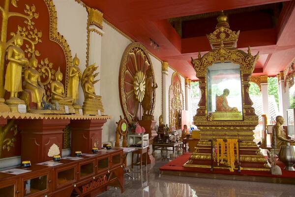 L’intérieur d’un temple, avec des statues dorées, un autel central et des sculptures complexes sur les murs.